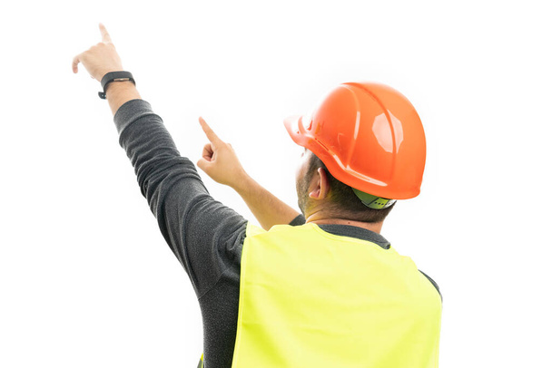 Dospělý muž konstruktor model v práci oblečení fluorescenční vesta a helma ukazující ukazováček prsty na prázdný copyspace izolované na bílém pozadí studia - Fotografie, Obrázek