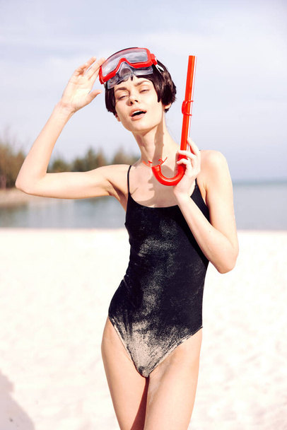 Mulher sorridente em máscara de snorkeling vermelho, um retrato de moda e diversão em uma praia tropical. - Foto, Imagem