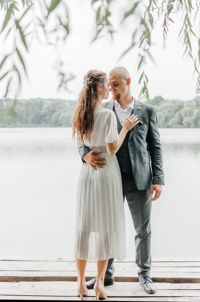 a noiva eo noivo abraçar e beijar na margem do lago - Foto, Imagem