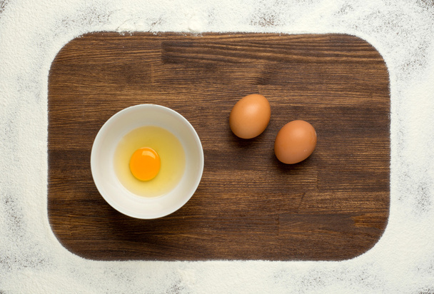 Flour and eggs on a wooden board - Fotó, kép