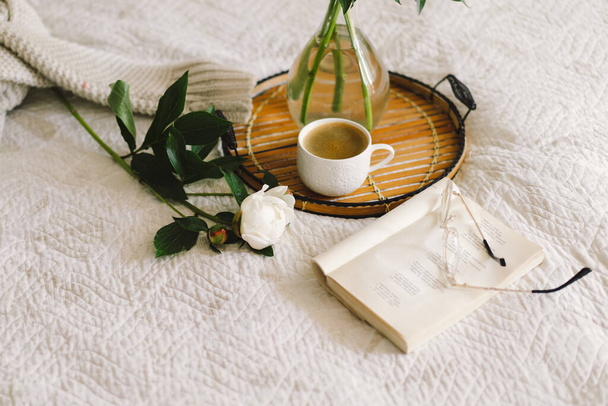 Csendélet részletek otthon belsejében nappali. Nyitott könyv szemüveggel, csésze kávé és csokor fehér rózsaszín bazsarózsa virágok. Olvass és pihenj. Hangulatos otthon - Fotó, kép