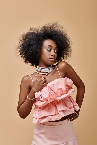 20 'li yaşlardaki rüya gibi Afro-Amerikalı kız şeftali rengi fırfırlı bluz ve bej arka planda pastel etekle poz veriyor. - Fotoğraf, Görsel