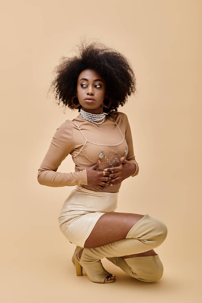 confident african american model in stylish outfit and thigh-high boots posing on beige backdrop - Photo, Image