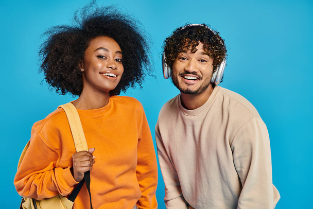 Un homme et une femme interracial se tiennent côte à côte sur un fond bleu, mettant en valeur l'unité et la convivialité. - Photo, image