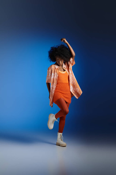 stylový africký americký model v vzorované košili a texturované šaty pózují na modrém pozadí - Fotografie, Obrázek