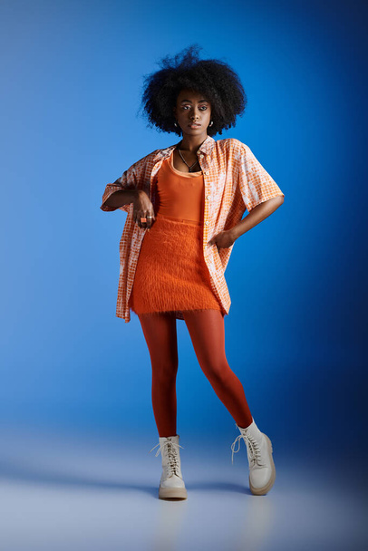 divatos afro-amerikai nő mintás ing és texturált ruha pózol kék háttér - Fotó, kép