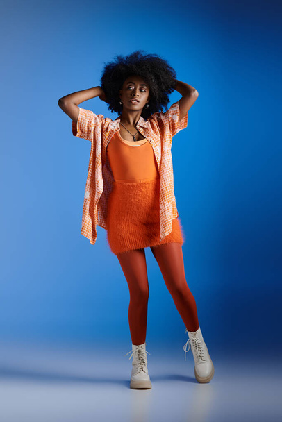 divatos afro-amerikai modell mintás ing és elegáns ruha pózol kék háttér - Fotó, kép