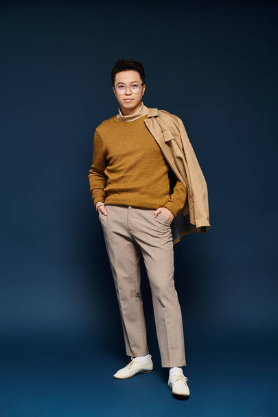 A fashionable young man poses confidently in a tan sweater and khaki pants, exuding elegance and style. - Zdjęcie, obraz