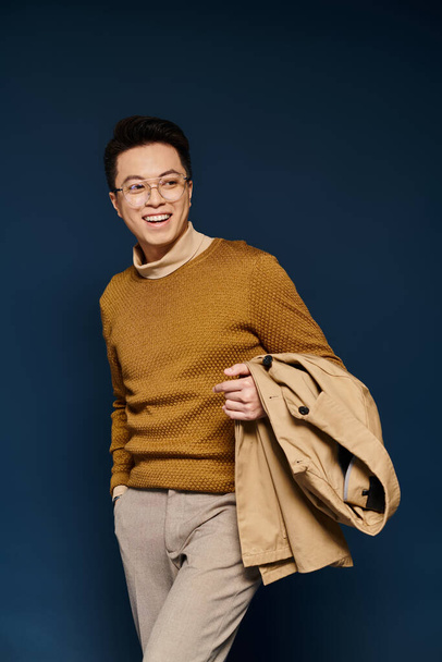 A fashionable young man exudes elegance in a brown sweater and tan pants, confidently posing for the camera. - 写真・画像