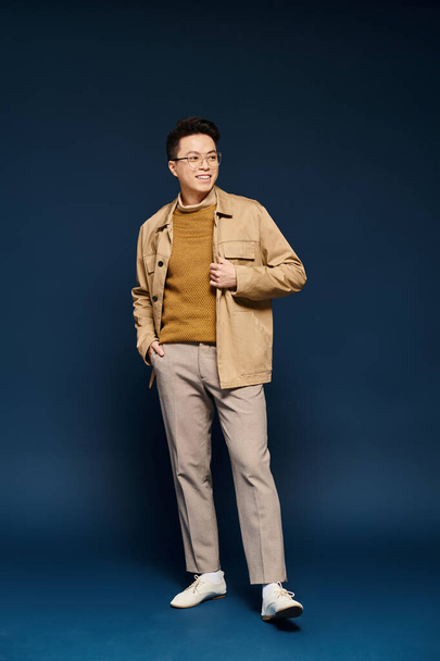 A fashionable young man in elegant attire striking a dynamic pose against a vibrant blue background. - Φωτογραφία, εικόνα