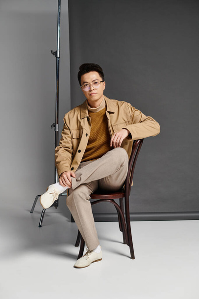 A fashionable young man in elegant attire sits on a chair - Фото, изображение