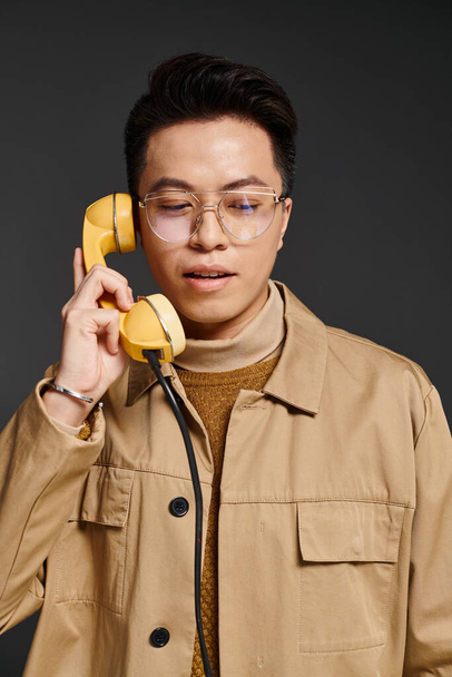 A fashionable young man in elegant attire playfully holds a phone up to his ear, on call. - Photo, Image