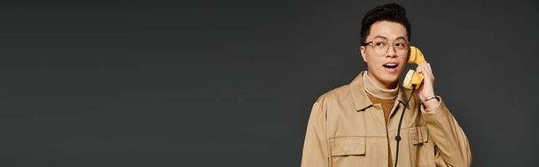Модний молодий чоловік в елегантному вбранні грайливо тримає смартфон - Фото, зображення