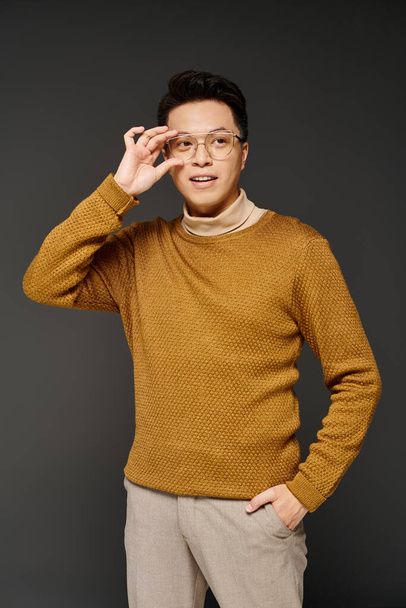 A fashionable young man in an elegant brown sweater striking a confident pose for the camera. - Foto, afbeelding