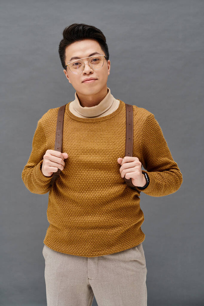 A fashionable young man poses confidently wearing a brown sweater, exuding elegance and style. - Photo, Image