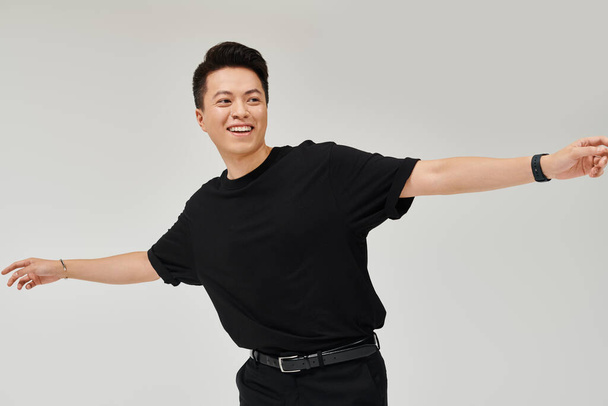 Модный молодой человек в черной рубашке и брюках занимает динамичную позу в элегантной обстановке. - Фото, изображение