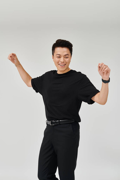 A stylish young man in a black shirt and pants strikes a dynamic pose, exuding confidence and sophistication. - Photo, image