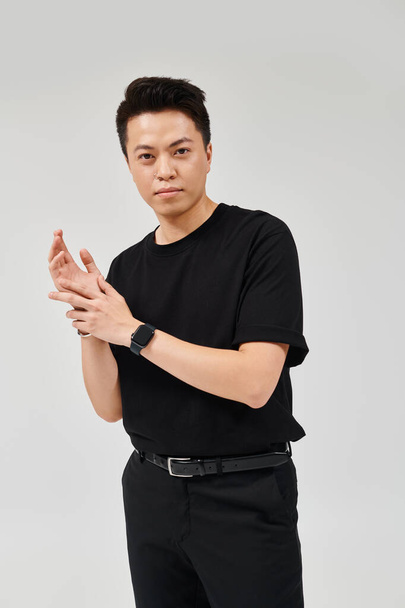 A fashionable young man strikes a confident pose in a black shirt and pants, exuding elegance and style. - Photo, image