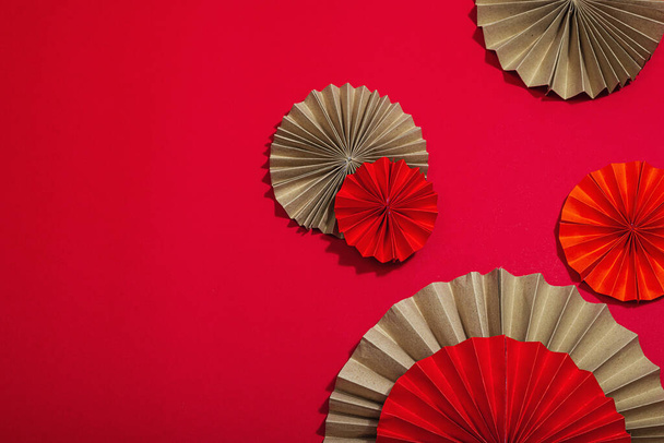 Happy Chinese New Year traditional concept. Oriental asian style paper fans on red background, minimal concept, flat lay, top view - Fotó, kép