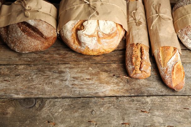 Different fresh bread, on old wooden table - Fotó, kép