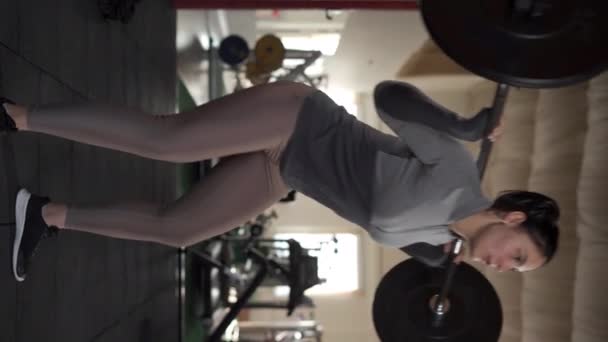Ağır metal halterci kadın halterci ağırlık kaldırma egzersizi yapıyor. Dikey video - Video, Çekim