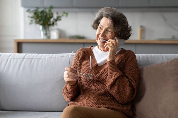 ハッピーヨーロッパの高齢女性は,友人,孫や家族と電話でコミュニケーションを話し,自宅で快適なソファに座っています - 写真・画像