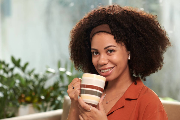 Портрет усміхненої латинки з чашкою кави - Фото, зображення