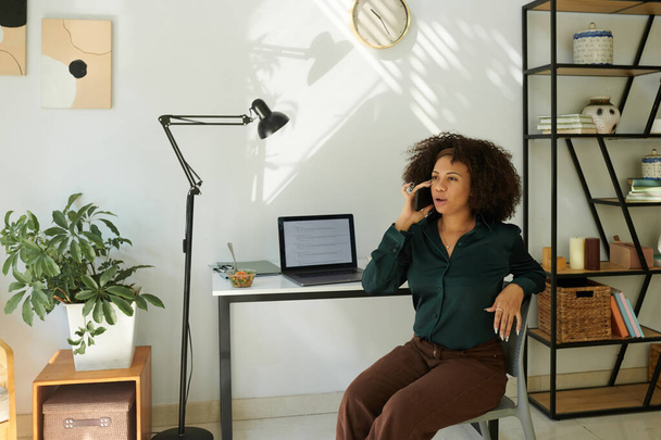 Розробник програмного забезпечення сидить на її домашньому офісі і розмовляє по телефону - Фото, зображення