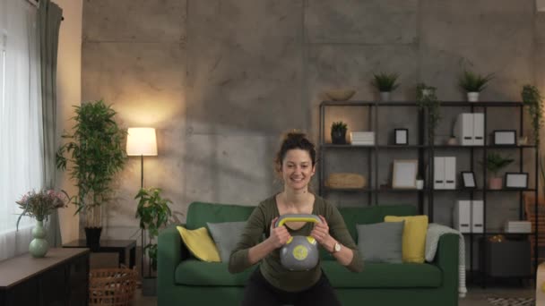 Una mujer adulta entrenando en casa uso kettlebell girya peso - Imágenes, Vídeo