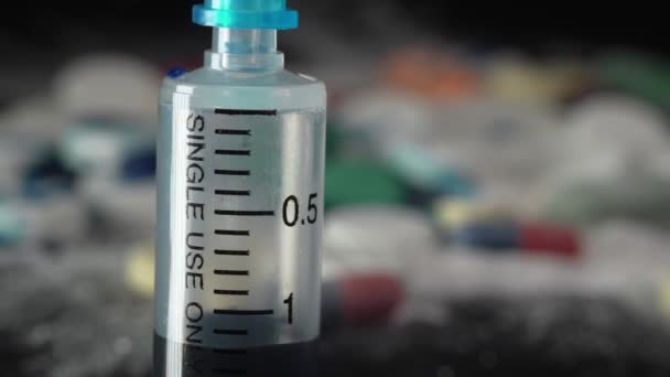Pistolet de seringue gros plan avec liquide bleu sur le fond des pilules et des médicaments - Séquence, vidéo