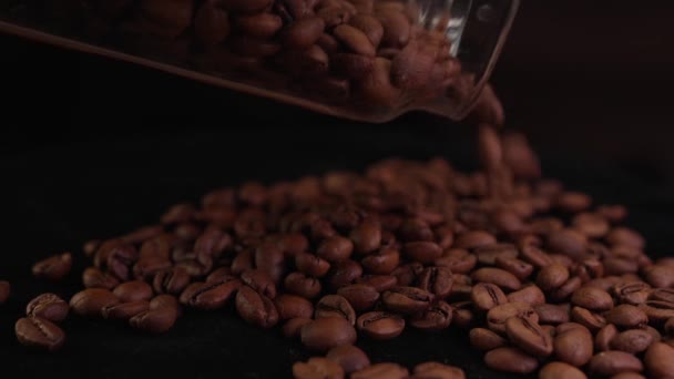 Chicchi di caffè versano da un barattolo di vetro che cade sulla superficie del caffè al rallentatore - Filmati, video
