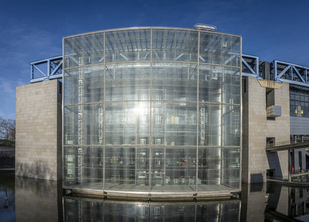 Paris, France - 01 27 2024: Villette Canal. Panoramic view of the glass facade of the building of the Science and Industry museum reflecting on the water basin - Photo, Image