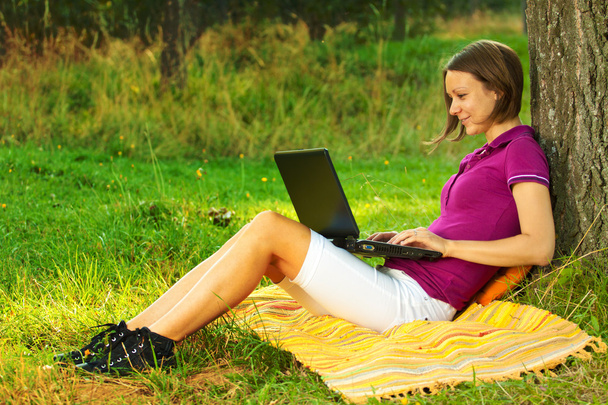 Bella donna eccitata con un computer portatile nel parco
 - Foto, immagini