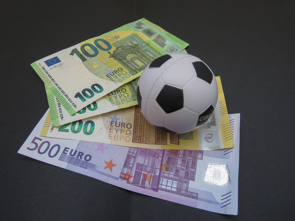 Billetes en euros moneda de la Unión Europea y una pelota de fútbol, útiles como corrupción o negocio en concepto de deporte - Foto, Imagen