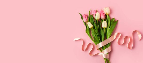 Belles tulipes avec ruban sur fond rose avec espace pour le texte. Journée internationale de la femme - Photo, image