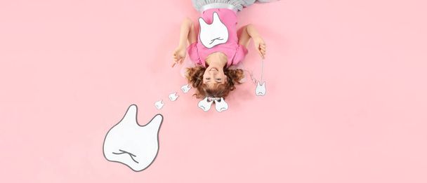 Зубная фея с бумажными зубами и волшебной палочкой на розовом фоне, вид сверху - Фото, изображение