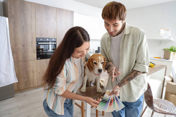 Casal jovem com paletas de cores de tinta e cão Beagle durante o reparo em sua nova casa - Foto, Imagem
