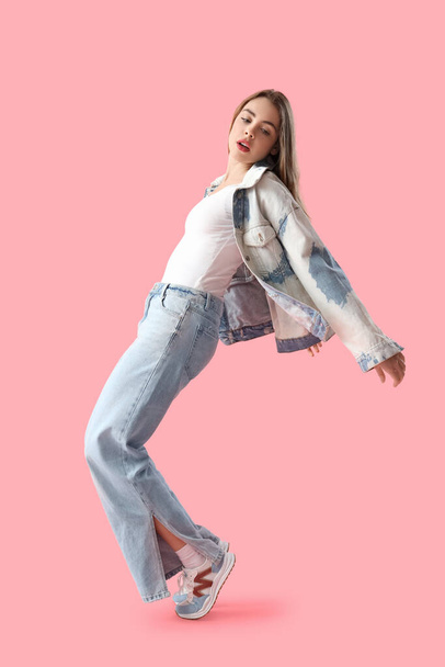 Young woman in light blue jeans on pink background - Photo, Image