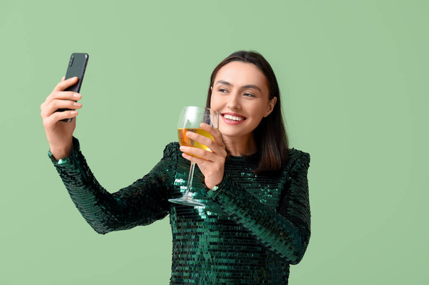 Gyönyörű fiatal nő egy pohár fehér bor, hogy szelfi zöld háttér - Fotó, kép