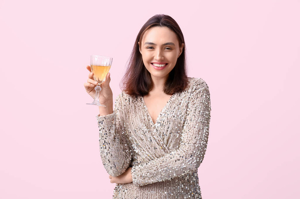 Beautiful young woman with glass of white wine on pink background - Фото, изображение