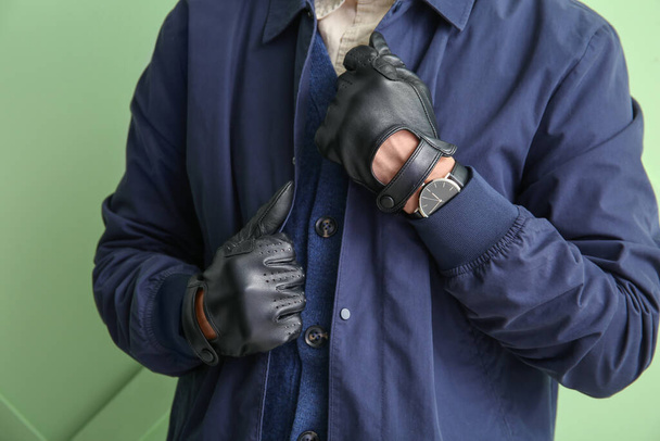 Homem na jaqueta elegante e luvas de couro preto contra parede de cor, close-up - Foto, Imagem