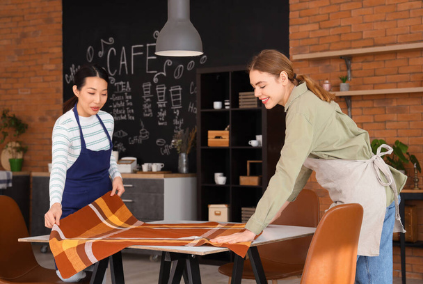 Female baristas putting cloth on table in coffee shop - Photo, Image