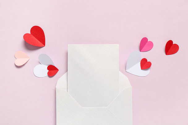 Composición con sobre, tarjeta en blanco y corazones de papel sobre fondo rosa, primer plano. Celebración de San Valentín - Foto, Imagen