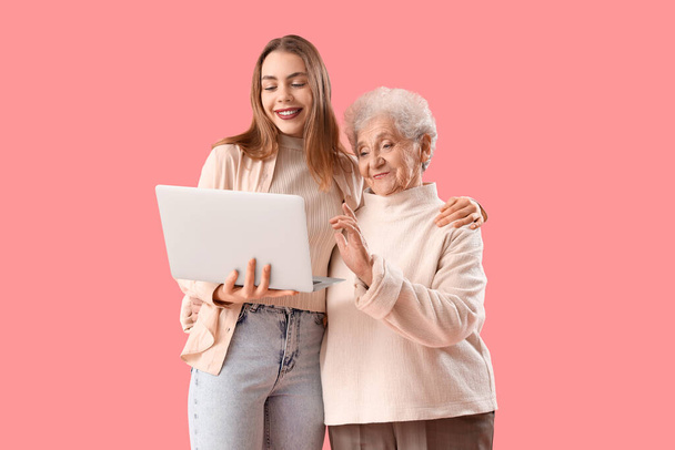 Jeune femme avec sa grand-mère vidéo bavarder sur fond rose - Photo, image