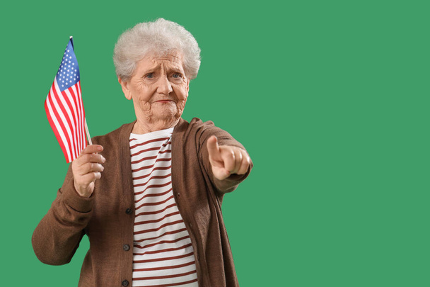 Ανώτερη γυναίκα με σημαία των ΗΠΑ δείχνει θεατή στο πράσινο φόντο. Έννοια της επίκλησης - Φωτογραφία, εικόνα