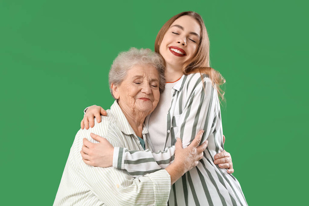 Młoda kobieta przytula babcię na zielonym tle - Zdjęcie, obraz