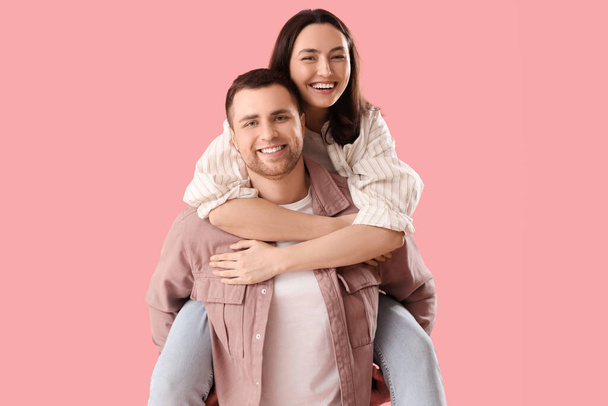 Feliz joven pareja abrazándose sobre fondo rosa - Foto, imagen