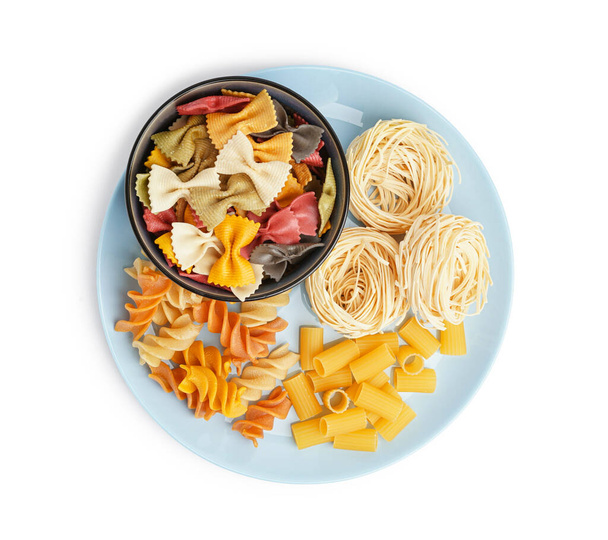Plate and bowl with different uncooked pasta on white background - Photo, Image