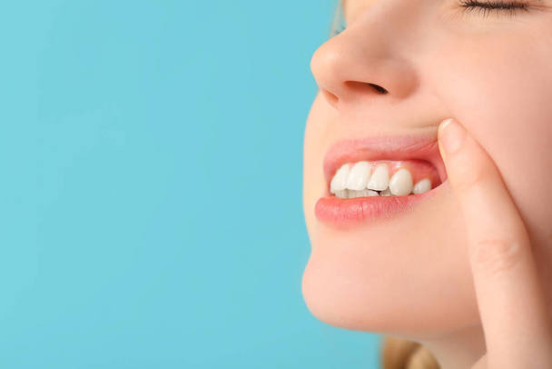 Ragazza adolescente che mostra i denti su sfondo blu, primo piano - Foto, immagini