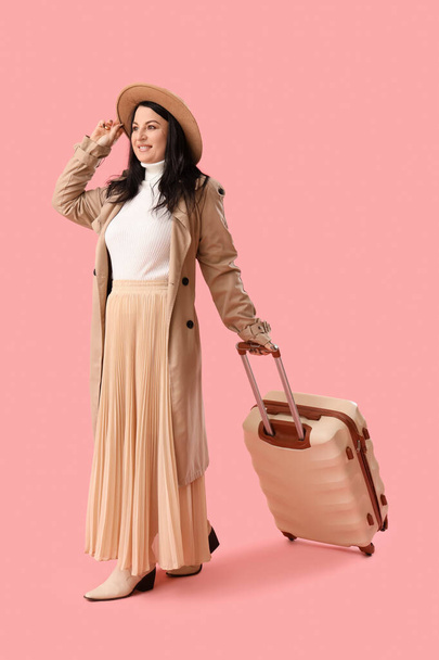 Красива стильна зріла жінка з валізою на рожевому тлі. Міжнародний жіночий день - Фото, зображення